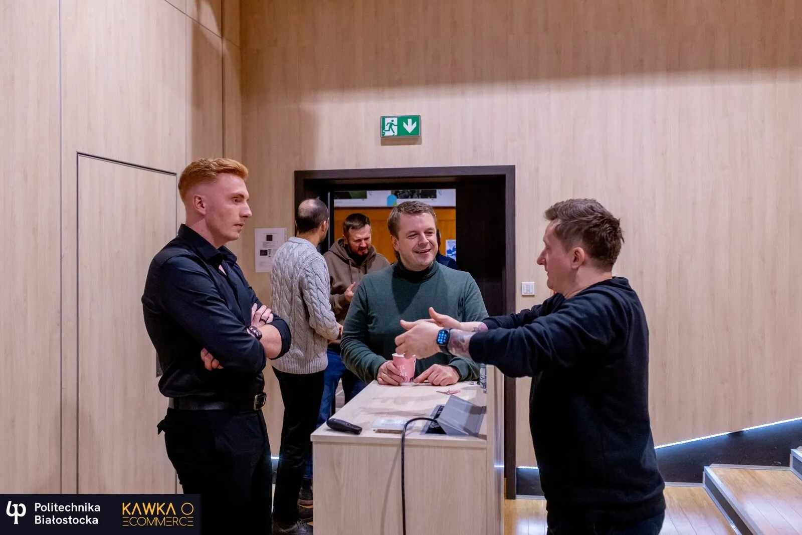 Four attendees talking around a table in the corridor at the Kawka o e‑commerce meet-up at Politechnika Białostocka.